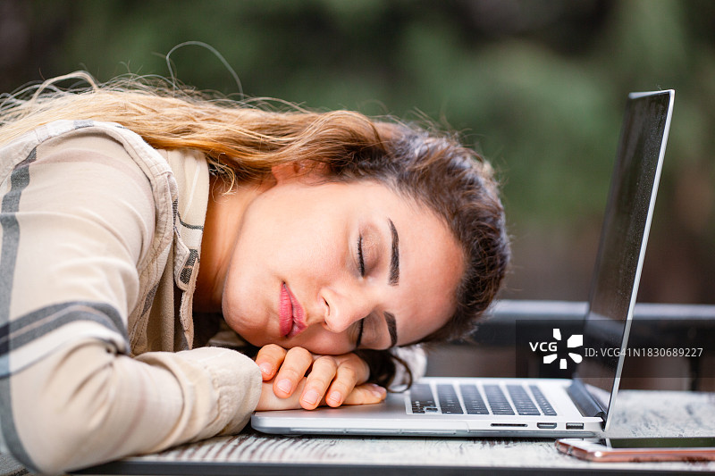 在笔记本电脑上睡觉的年轻漂亮女子图片素材