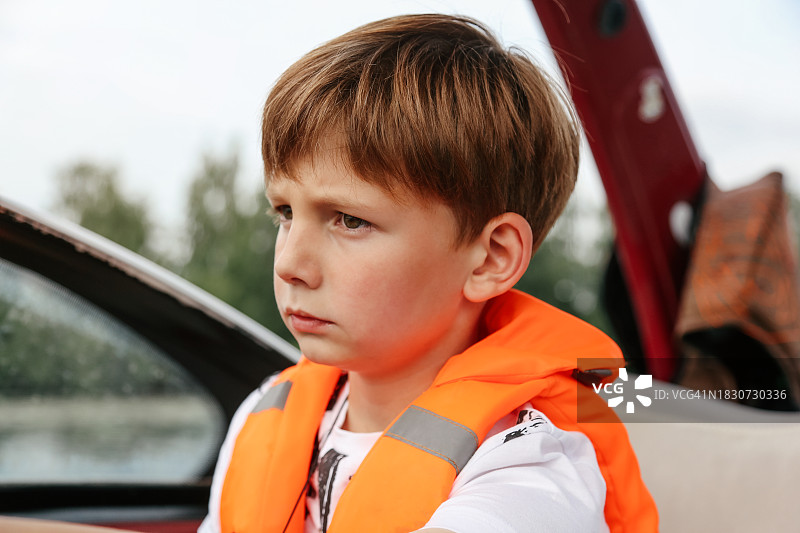 穿着橙色救生衣乘坐快艇的8-9岁男孩图片素材