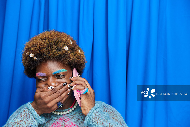 站在蓝色影楼风格窗帘前，穿着时髦、古怪的人图片素材