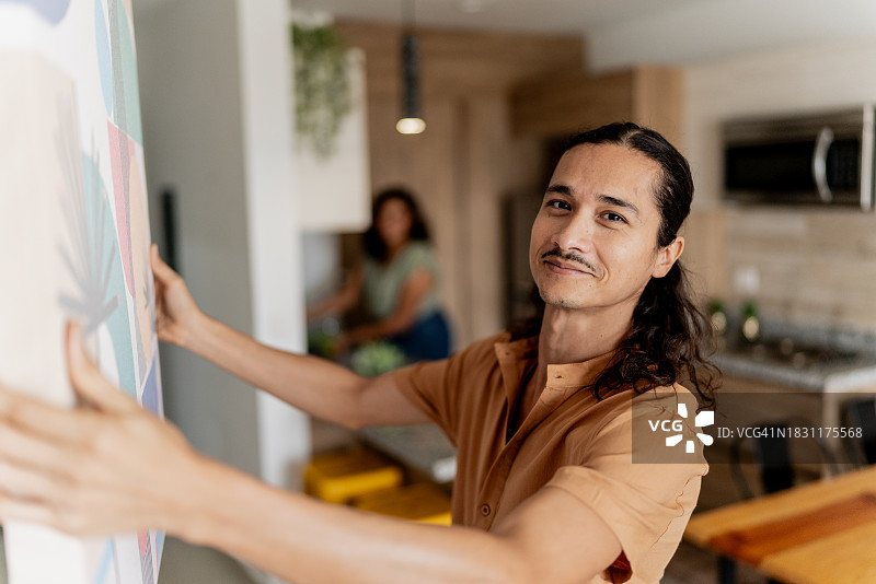 中年男子在家中墙上挂相框的肖像图片素材