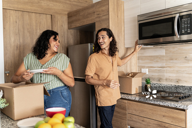 中年夫妇在新家厨房里打开装有厨房用具的箱子图片素材