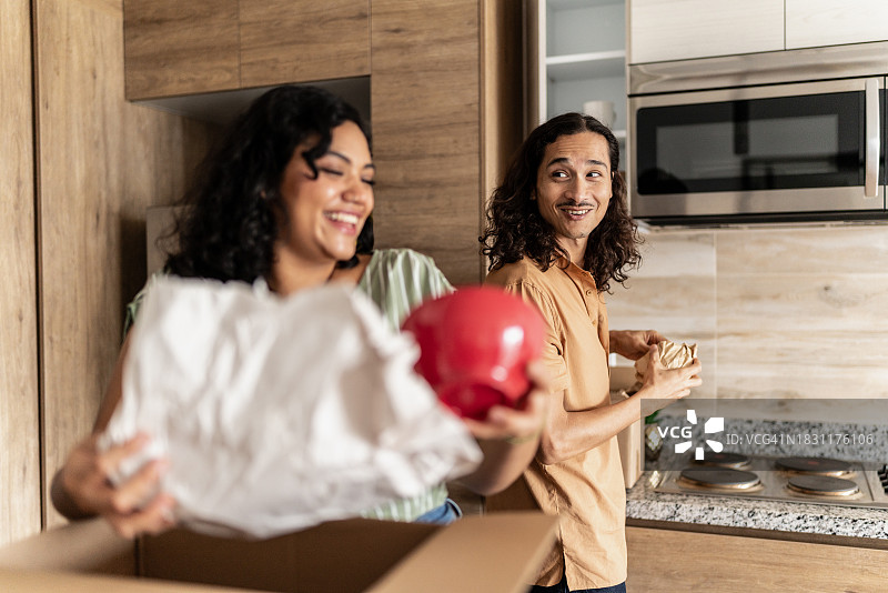 中年夫妇在新家厨房里打开装有厨房用具的箱子图片素材