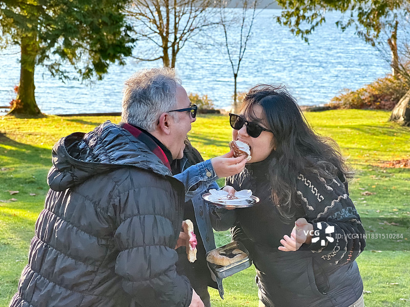 多种族家庭品尝用可重复使用钢制容器包装的野餐糕点图片素材