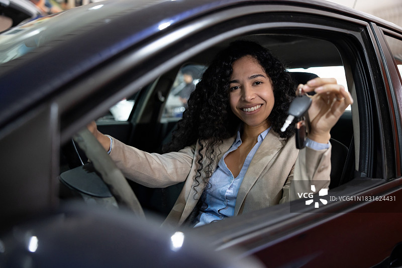 快乐的女人在汽车经销店拿着车钥匙图片素材