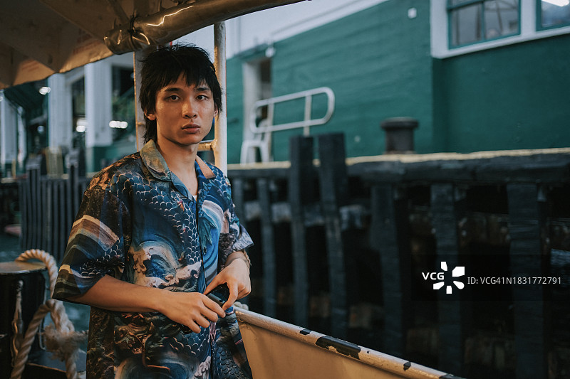 在九龙海港渡轮上，一位态度很酷的香港年轻人看着镜头图片素材