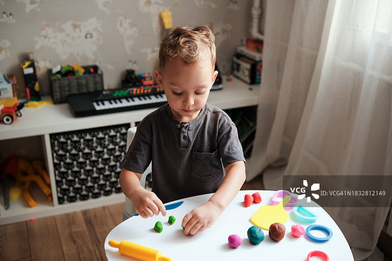 小男孩在桌旁玩橡皮泥，感官活动图片素材
