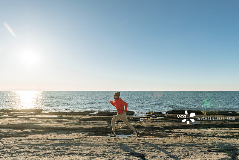 日落时分沿海边跑步的青年图片素材