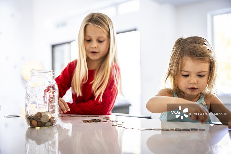 年轻女孩在厨房柜台上数硬币图片素材