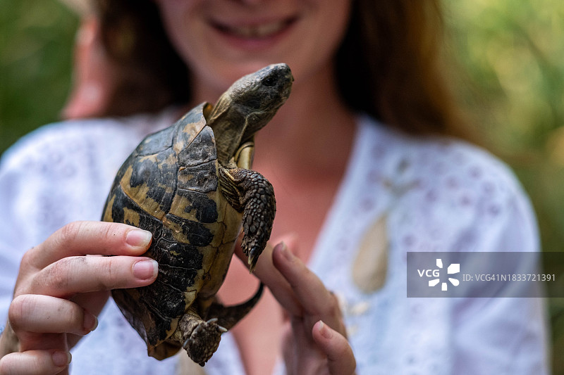 在海滩上，女人手里拿着一只乌龟图片素材