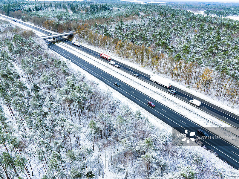从上方看到的穿过白雪皑皑森林景观的公路图片素材