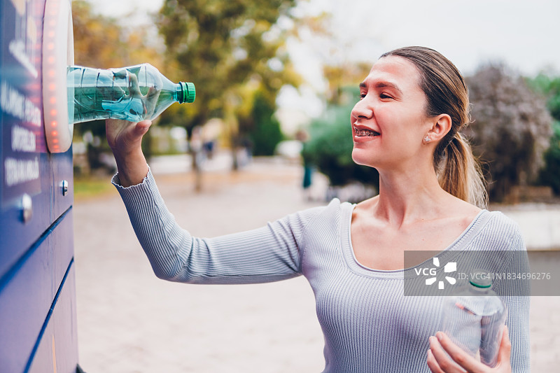 年轻女子在机器中回收塑料瓶图片素材