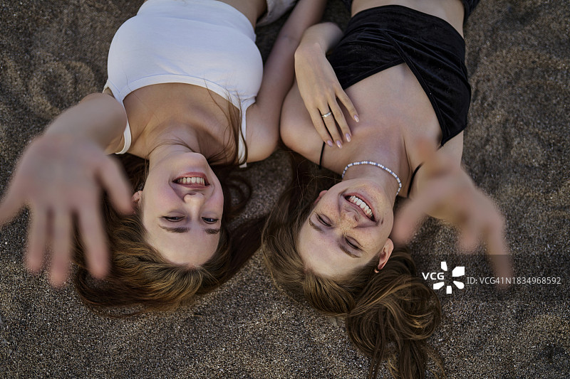 年轻女性躺在沙滩上举起双手图片素材