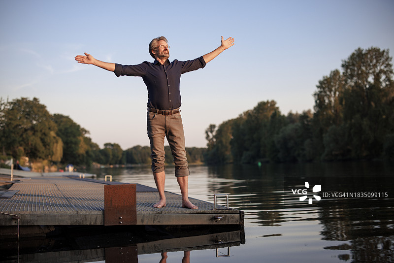 在码头上伸开双臂站立的年长男人图片素材