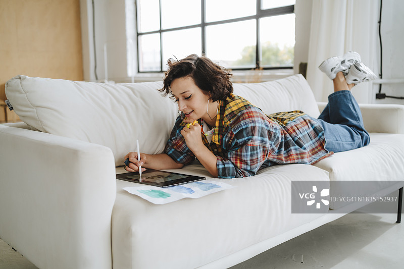 年轻插画师在办公室沙发上使用绘图板图片素材