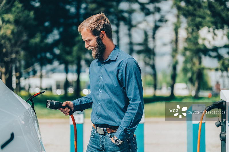 男人给电动汽车充电图片素材