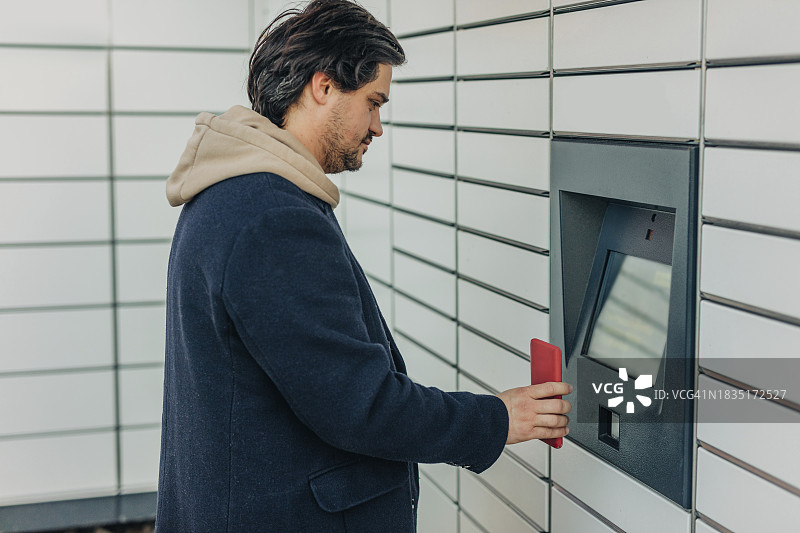 男人在包裹储物柜机器上用智能手机扫描二维码图片素材