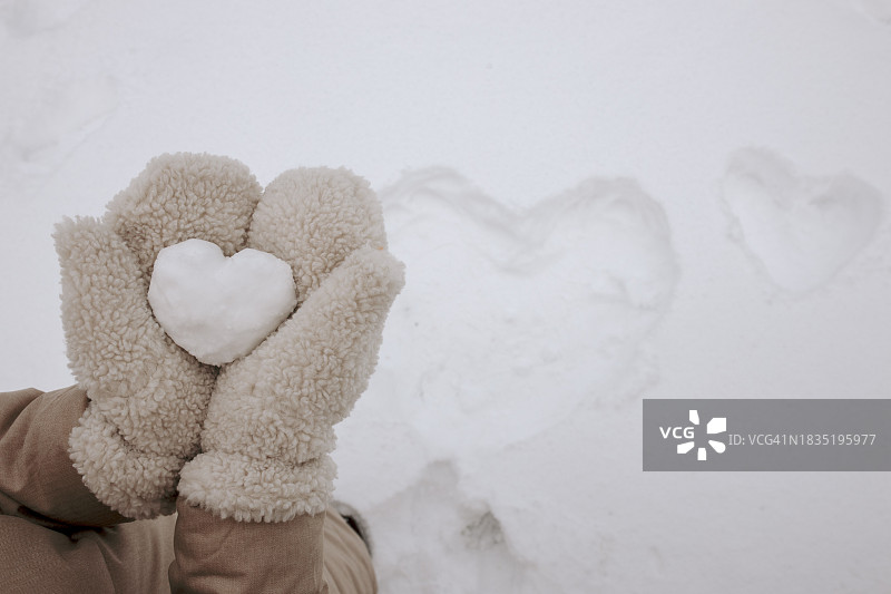 冬天戴手套，手捧心形雪的女人图片素材
