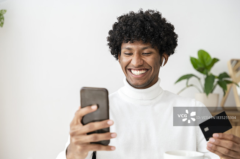 快乐的男人通过信用卡在智能手机上进行网上购物图片素材