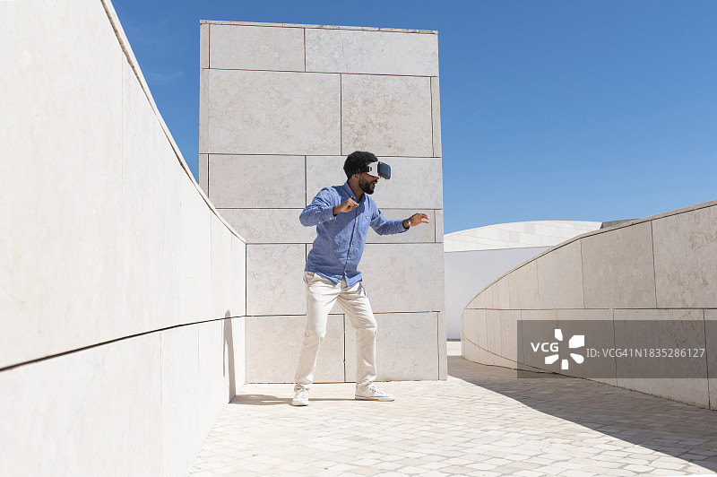 男人在晴朗的一天站在墙边观看虚拟现实模拟器图片素材