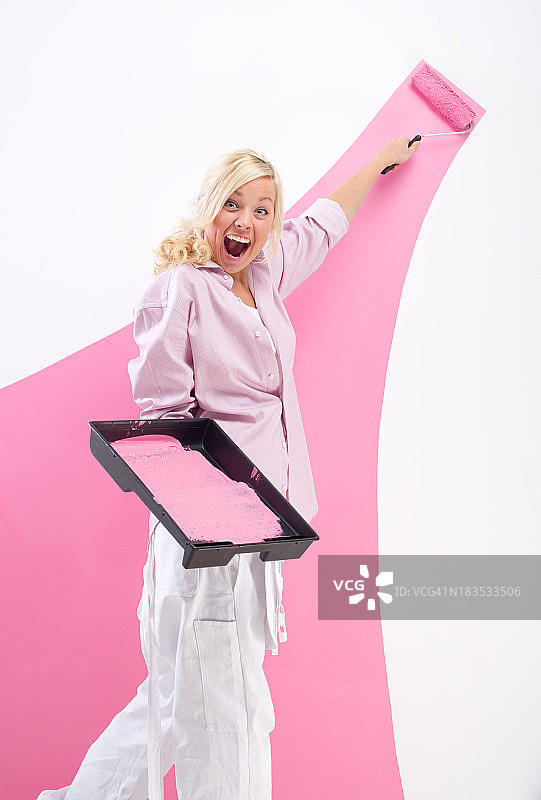 年轻女人把墙壁刷成粉红色图片素材