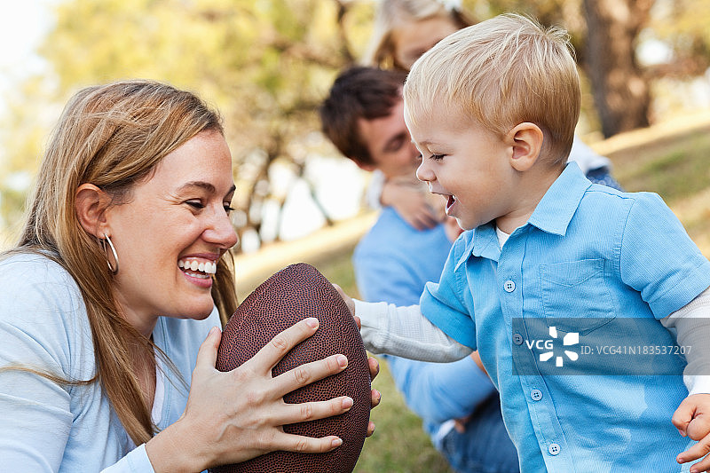 母亲和年幼的儿子在公园踢足球图片素材