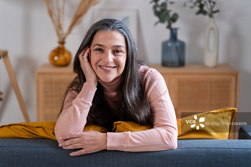 坐在客厅沙发上的微笑老年妇女肖像图片素材