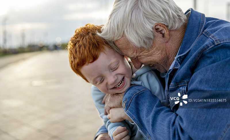 在公园里拥抱孙子的微笑爷爷图片素材