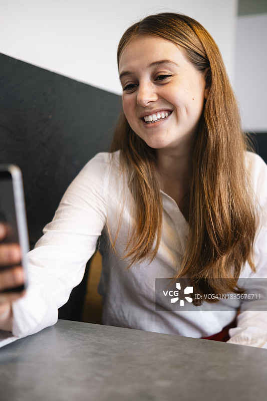 微笑的女商人在工作场所通过手机进行视频通话图片素材