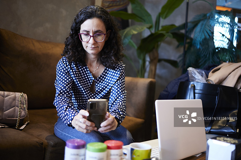 中年妇女用手机拍摄药瓶，然后在电脑上搜索信息图片素材