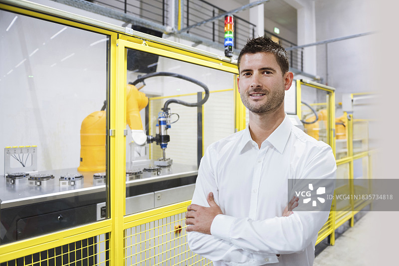 笑容满面的工程师在工厂交叉双臂站立图片素材