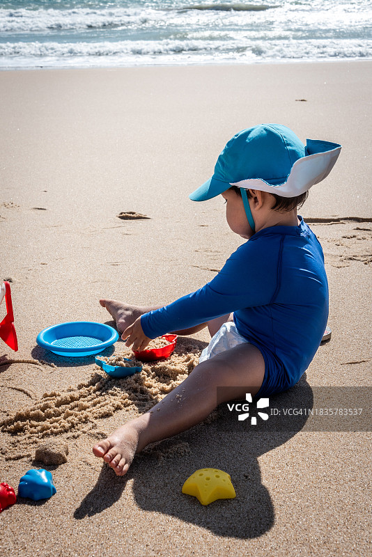 男孩在海滩上玩沙子图片素材