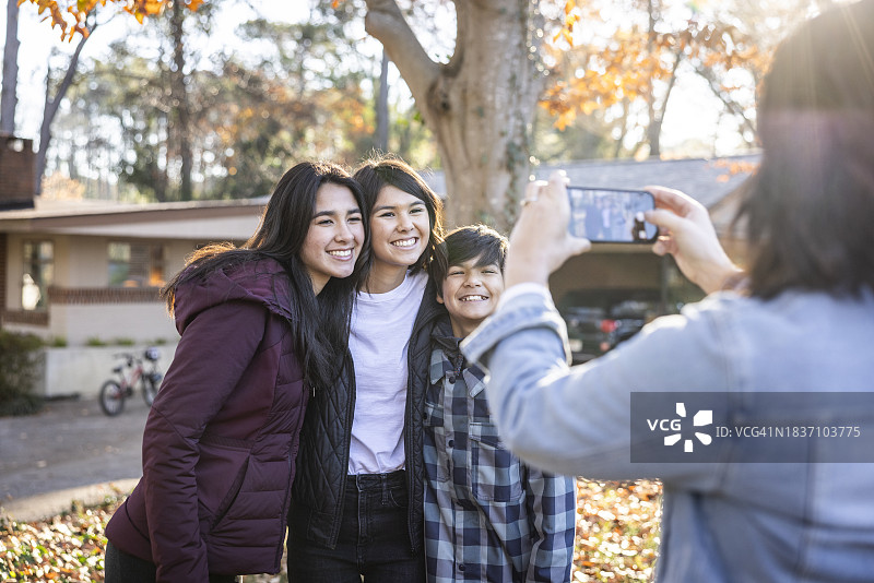 母亲在前院给青少年子女拍照特写图片素材