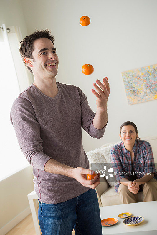 男人玩转橙子，女人在观看图片素材