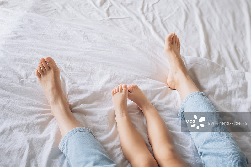 白色床单上母子双腿。产假。亲子关系。心理治疗图片素材