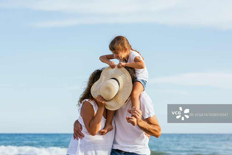 海边亲情：家庭在阳光明媚的日子里享受海滩图片素材