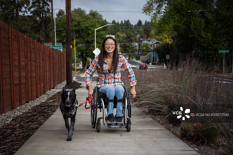 坐轮椅的亚洲妇女遛宠物狗图片素材