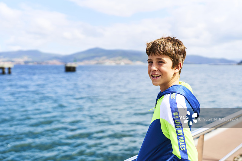 男孩倚靠海边栏杆侧面照图片素材