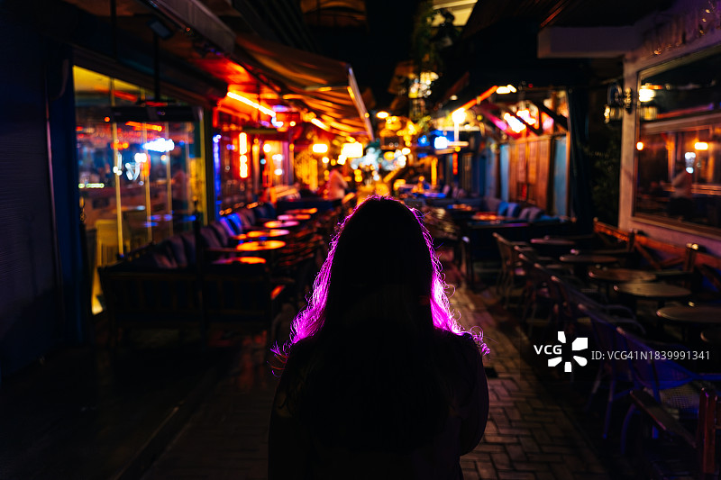站在霓虹灯闪烁的夜色中的女人图片素材