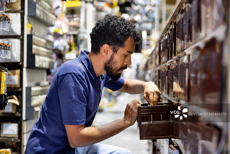 五金店的零售店员在储藏室寻找螺丝图片素材