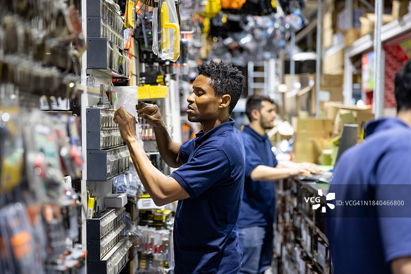 五金店的零售店员在储藏室寻找螺丝图片素材