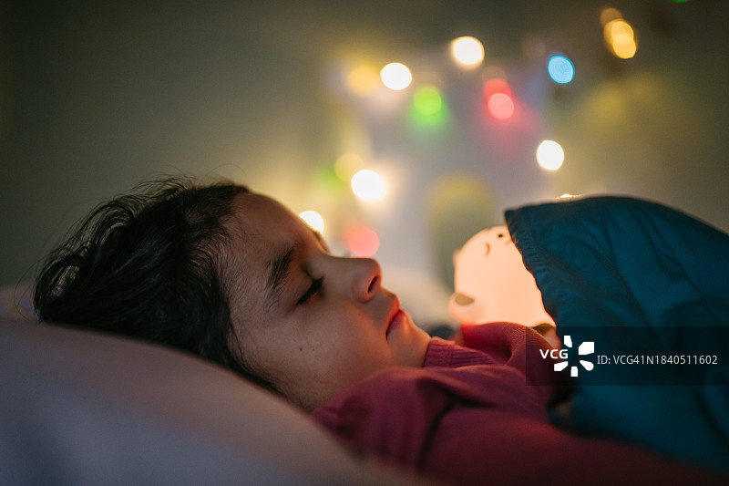 圣诞夜，抱着发光玩具入睡，梦见圣诞老人的可爱小女孩图片素材