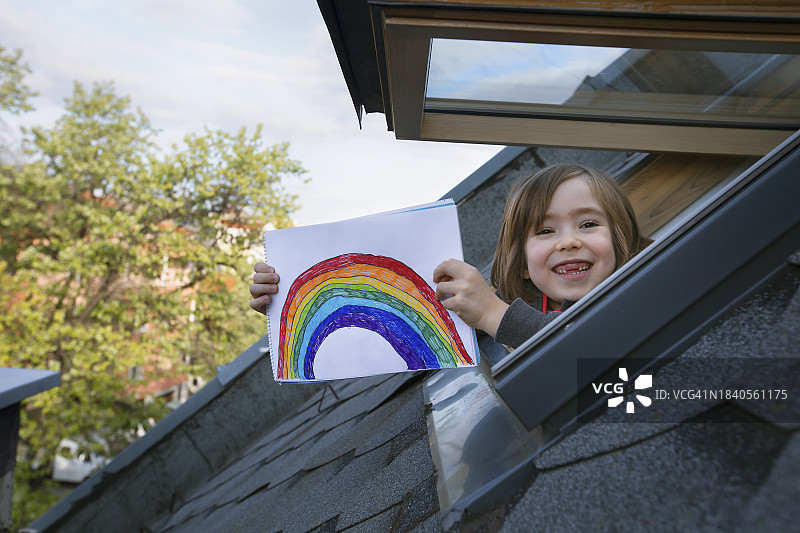 微笑儿童隔着窗户展示他的画作图片素材