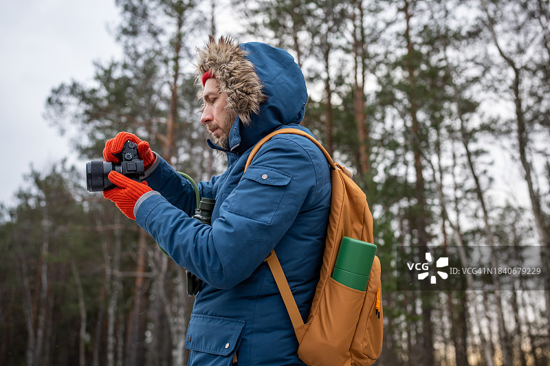 专业摄影师站在森林里，手持相机，拍摄自然风光图片素材