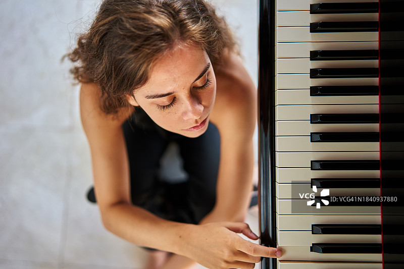 年轻女子坐在地板上弹钢琴图片素材