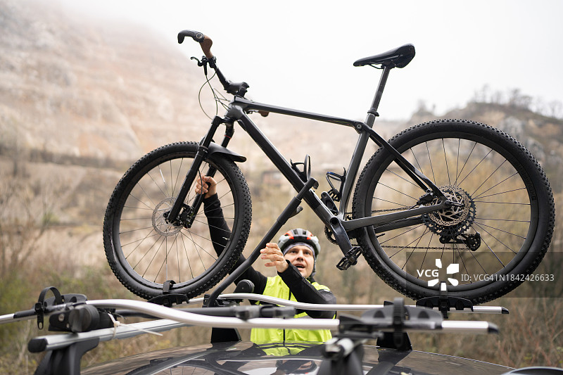 山地自行车手从车顶卸下自行车图片素材