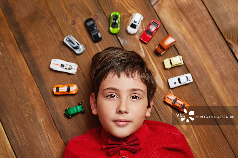 快乐的男孩躺在地上，周围都是玩具车图片素材