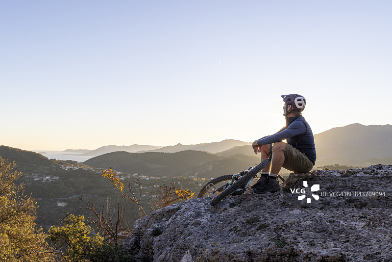 中年男人骑自行车在山脊上休息图片素材