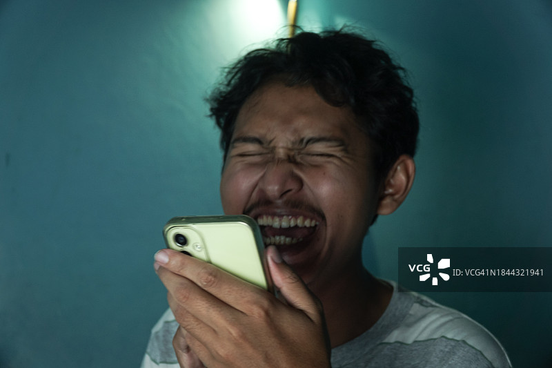 查看智能手机时微笑的亚洲青少年图片素材