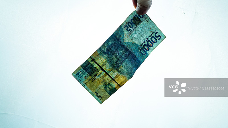 人手拿着的五万印尼盾在高曝光下变得半透明图片素材