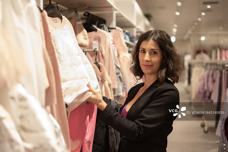 在购物中心服装店寻找衣服的40岁女性图片素材